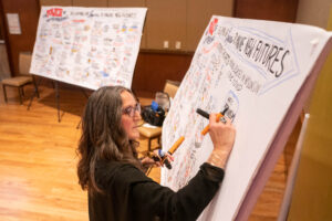 Sherrill Knezel draws on a large sheet of white paper.